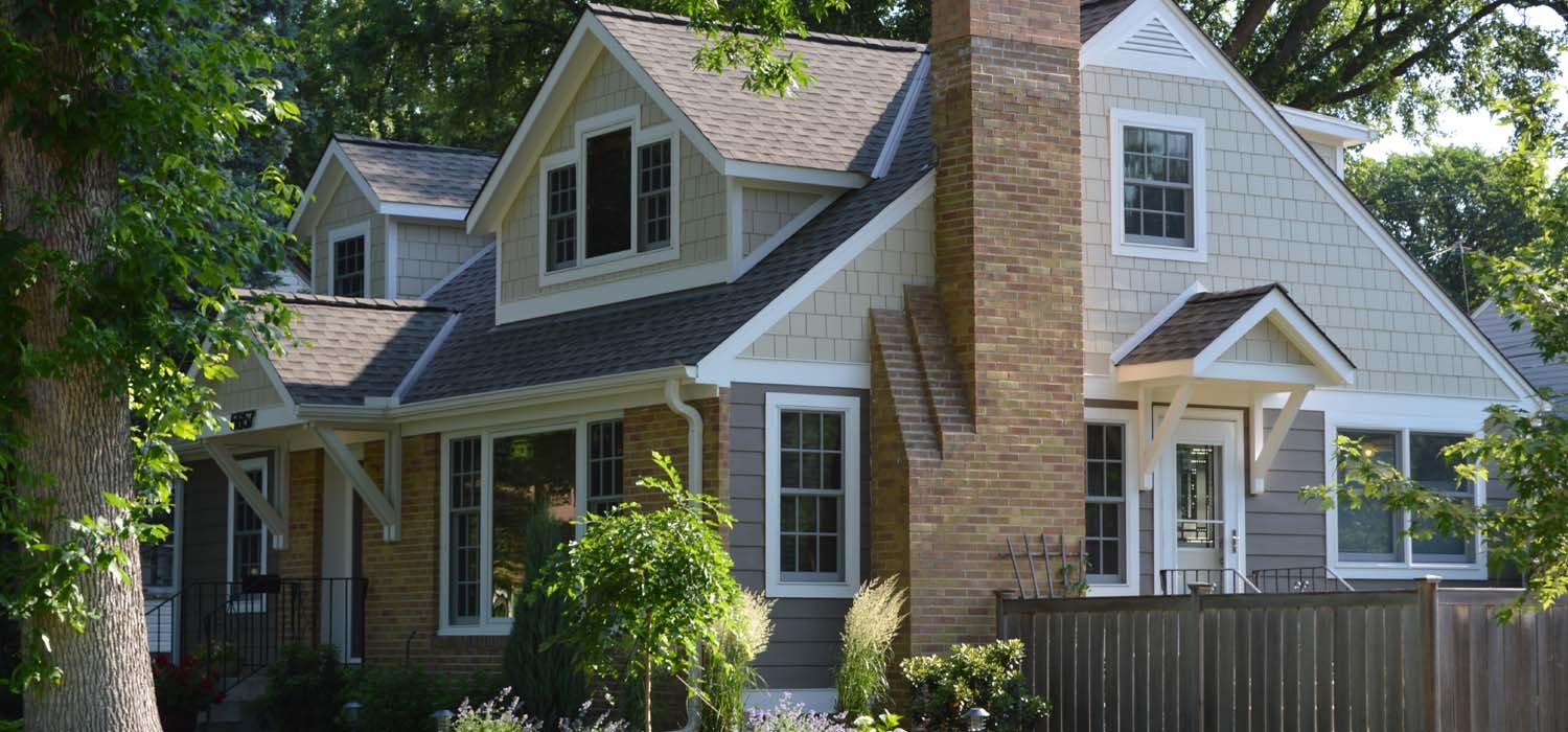 Traditional home renovation with shingle siding, brick details, and landscaped garden